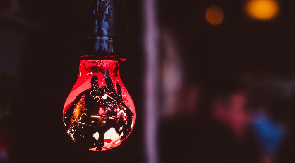 An image of a red coloured lightbulb with abstract shapes reflected on it; the lightbulb pops up as it is displayed on a dark background